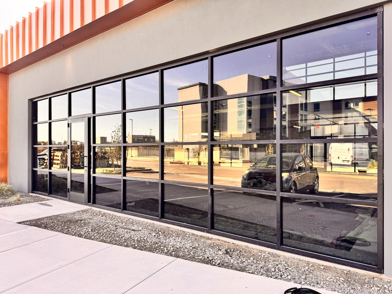 After — finished full-height storefront glazing installed at Northside, with the dark anodized aluminum framing reflecting the surrounding shopping center