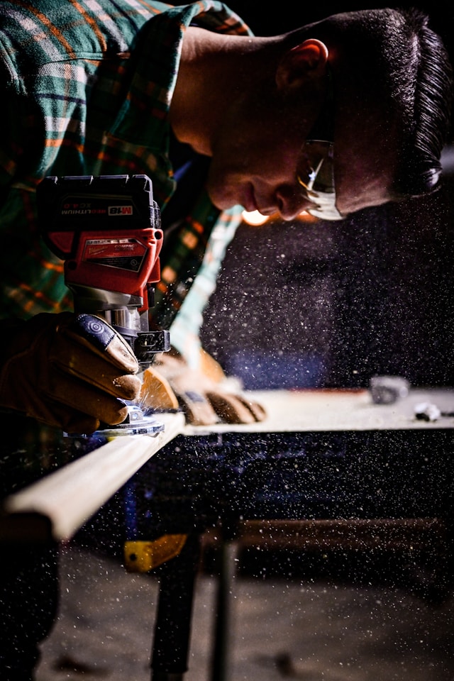 Trade partner operating a cordless power tool on a commercial construction jobsite, with sawdust catching the light